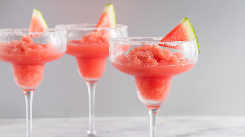 Pink sorbet spritzer served in margarita glasses with a watermelon wedge