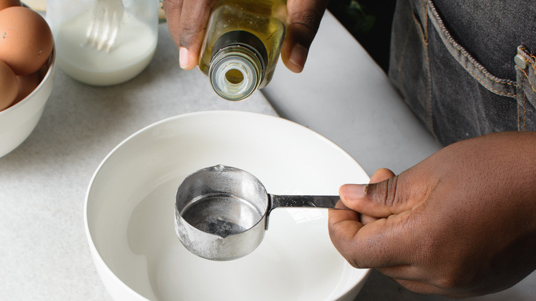 Pouring oil into measuring cup over bowl