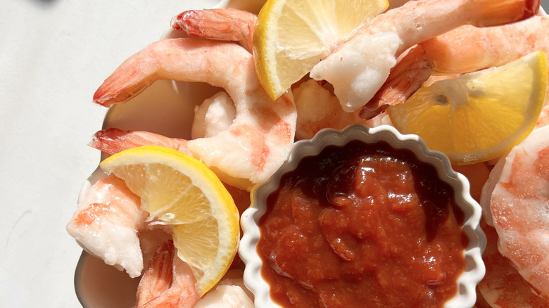 Bowl of shrimp cocktail with lemon wedges
