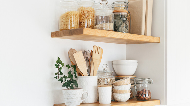 Open kitchen shelving stocked with food jars, dishes, and utensils