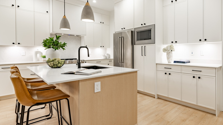 White modern kitchen with small black cabinet knobs and simple linear drawer pulls