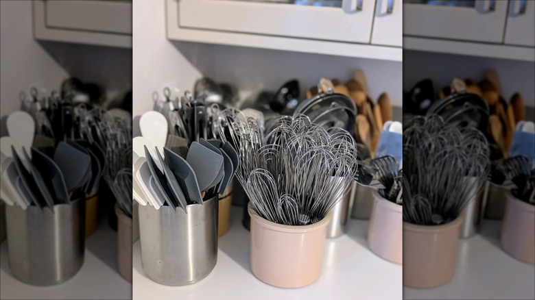 Crocks and metal containers on a countertop full of utensil organized by type