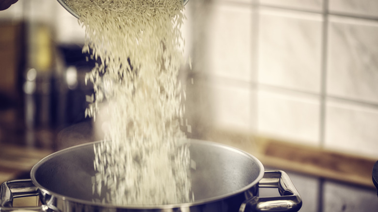 Pouring dry rice into a large pot to cook