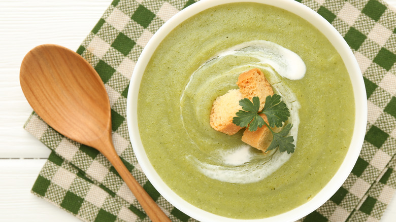 Bowl of broccoli soup beside a wooden spoon
