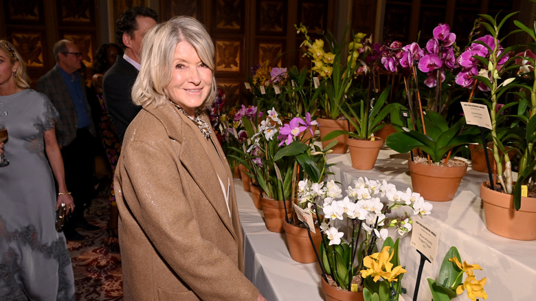 Martha Stewart smiling at an event next to orchids