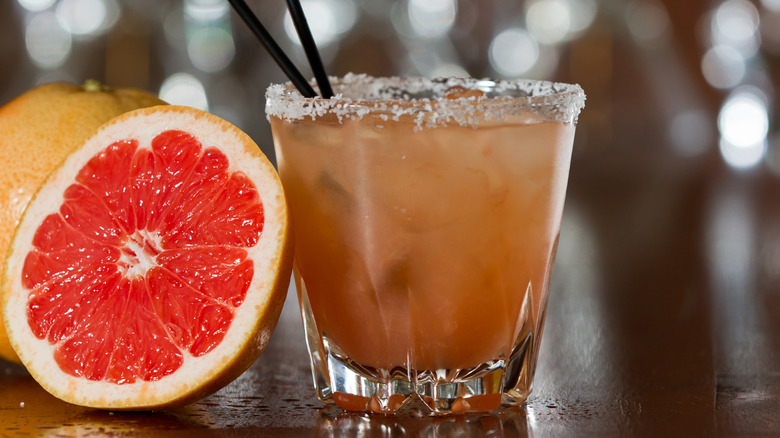 A close up of a standard salty dog with a sliced grapefruit next to it
