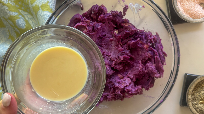 hand adding sauce to potatoes
