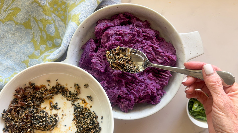 hand spooning seeds on purple potatoes