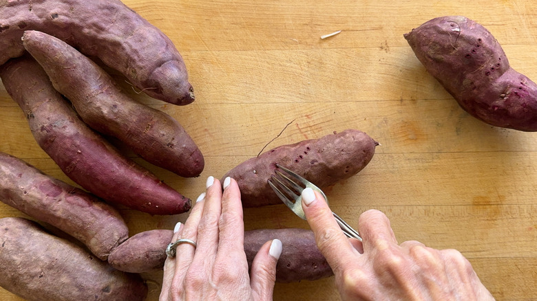 hand poking purple potato with fork