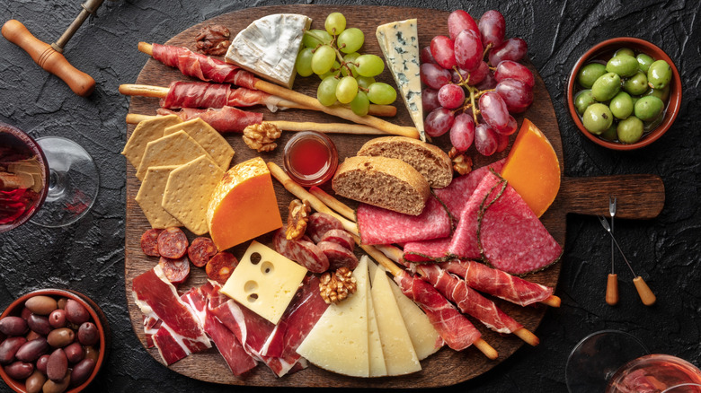 a charcuterie and cheese board with bread, grapes, and olives