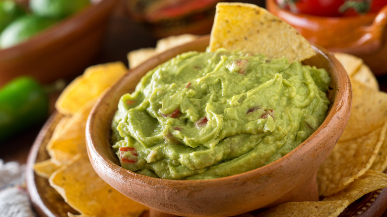 Creamy guacamole in a wooden bowl with tortilla chips