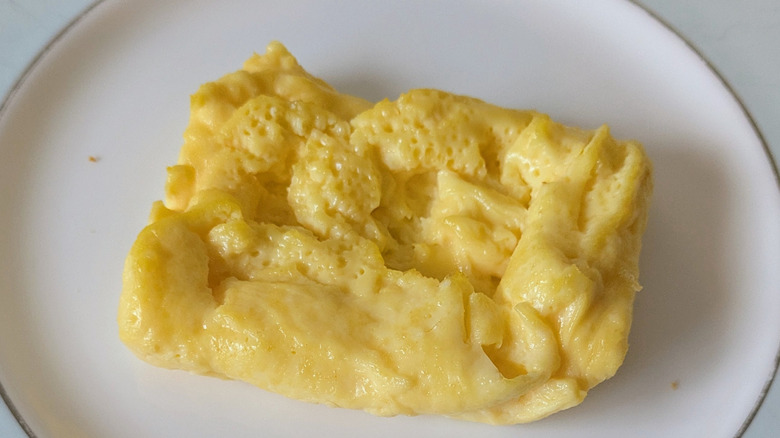 A single serving of scrambled eggs, yellow in appearance, and formed into a rectangular shape on a blue and white plate
