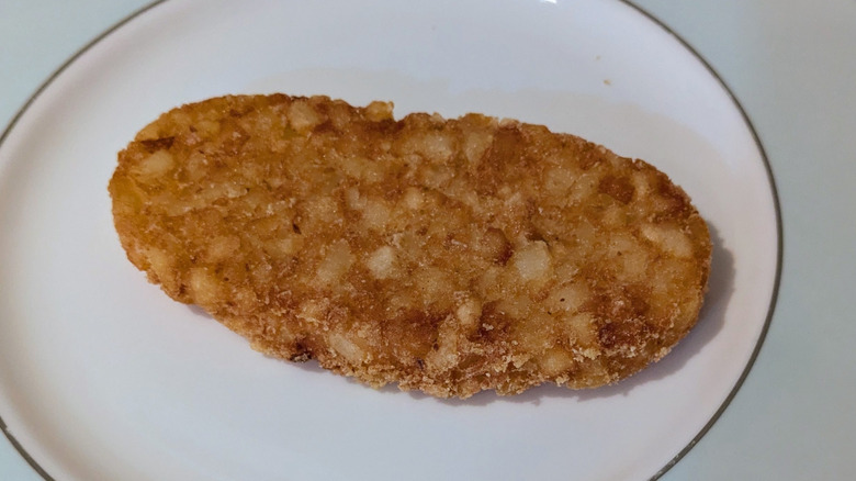 A golden-fried oval-shaped hash brown is served on a blue and white plate