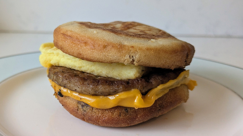 A sausage patty, folded fluffy egg, slice of yellow cheese are sandwiched in between two maple-syrup infused griddle cakes
