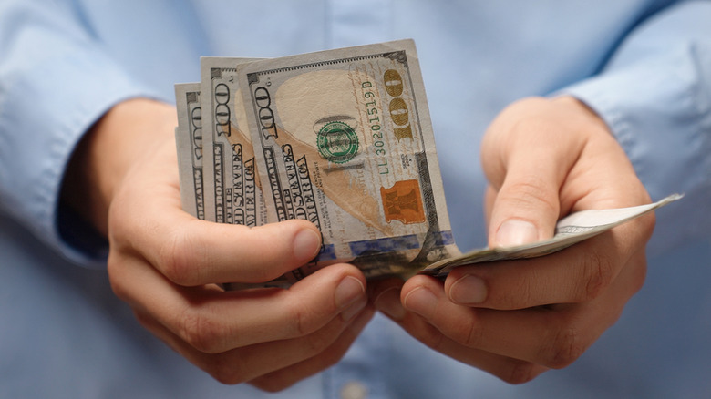 Hands holding some American $100 bills