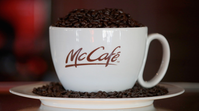 McCafé-branded white ceramic mug filled with coffee beans.