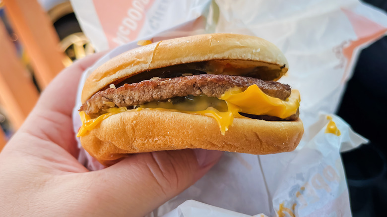 A person holding a McDonald's McDouble cheeseburger
