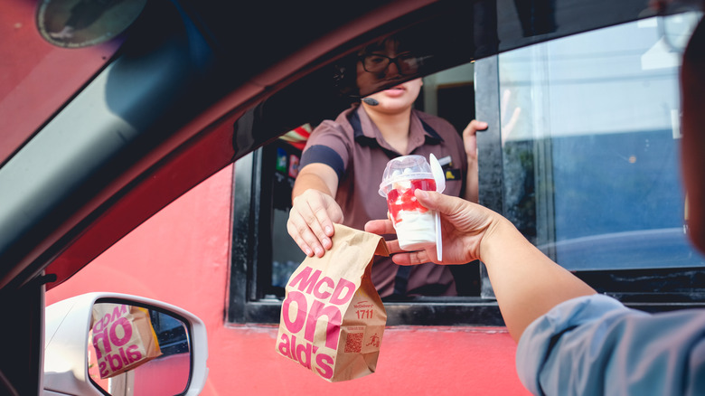 McDonald's worker hands order to driver in a car