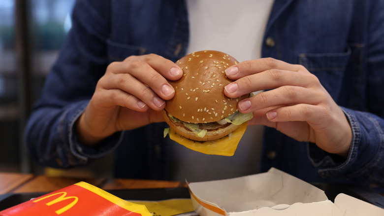 Person holding McDonald's burger, eating at a table