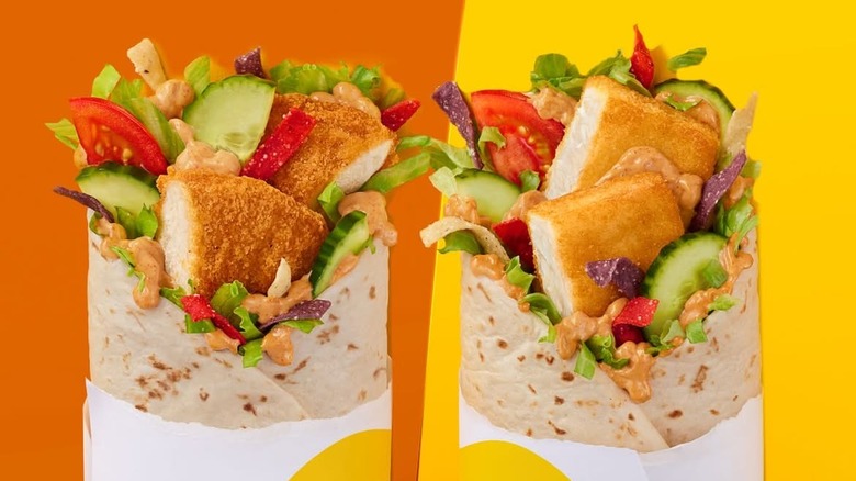 Two McDonald's McWraps, one with chicken and another with fish, side by side on orange and yellow background