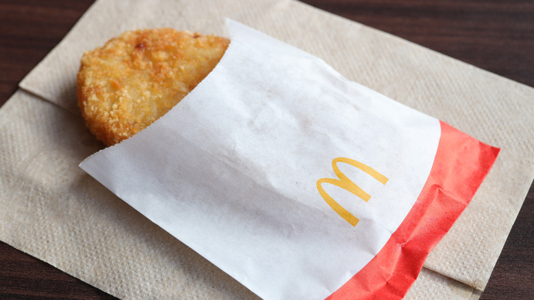McDonald's hash brown patty in paper sleeve.