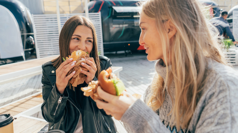 Two women eating fast food sandwiches
