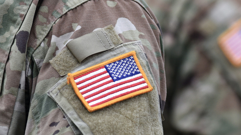 An American flag insignia on the sleeve of a camouflaged U.S. military uniform