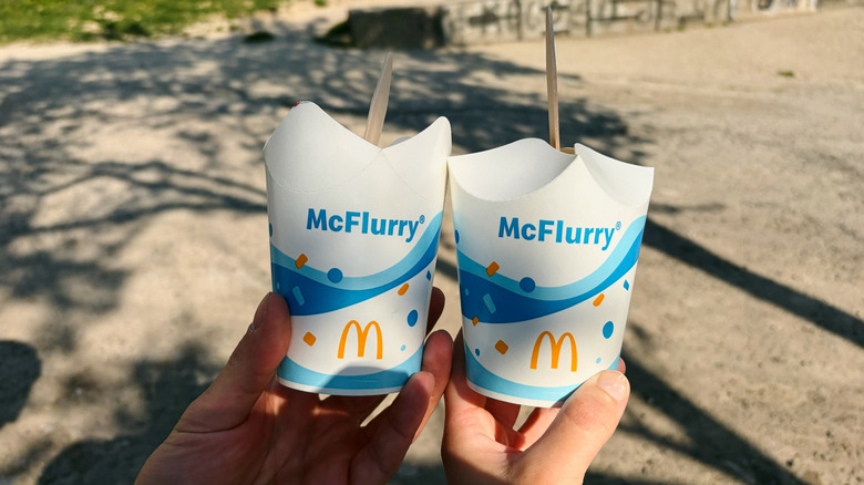 two hands hold out 2 McFlurry ice creams outside