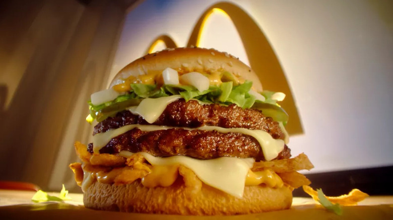 A close-up of a towering McDonald's Big Arch burger sitting on a restaurant table