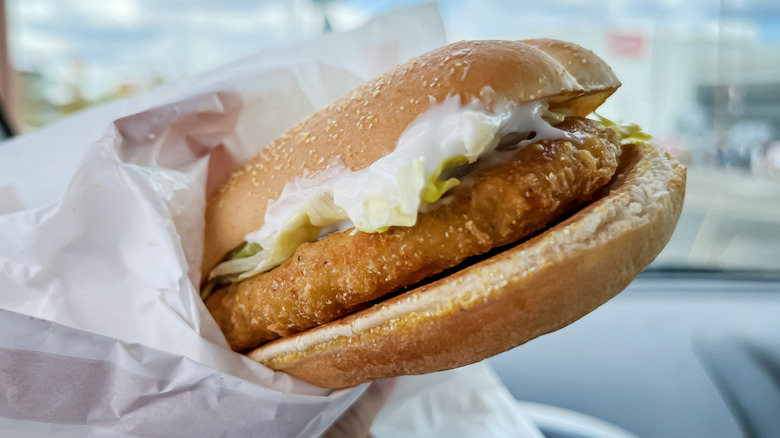Foodie holding a McChicken sandwich in the car