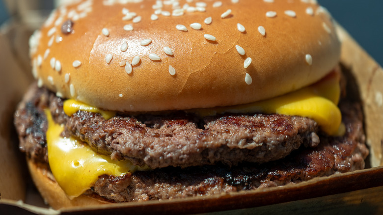 Close up of a McDonald's Quarter Pounder with cheese melting out the sides and a sesame seed bun