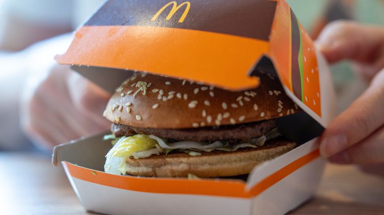 A person opening a McDonald's hamburger box at a restaurant table