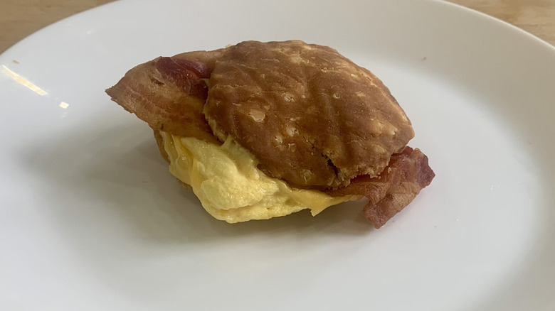 Burger King bacon egg and cheese biscuit on a white plate with wood background