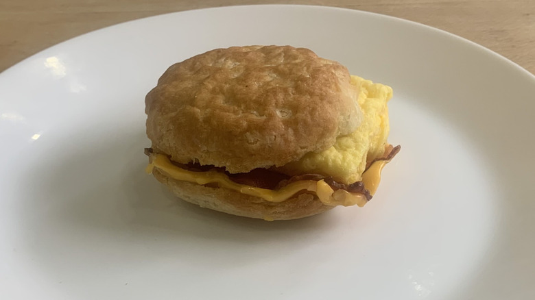 McDonald's bacon egg and cheese biscuit on a white plate with wood background
