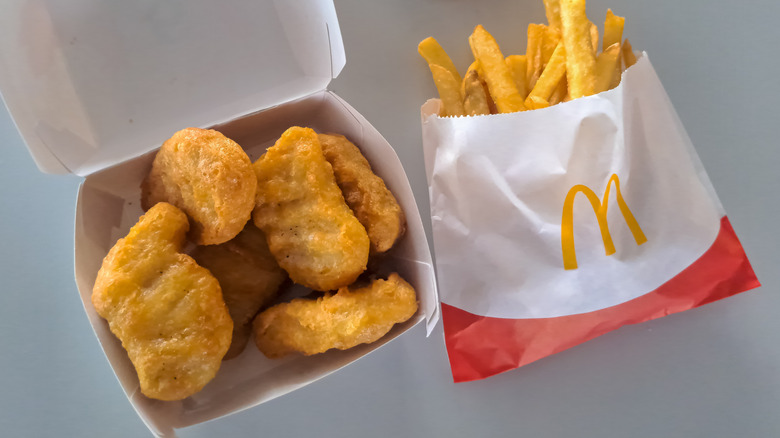 Overhead view of an open carton of McDonald's McNuggets beside a paper sleeve of french fries