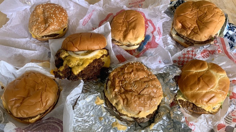 Fast food double cheeseburgers in open wrappers spread out on a table