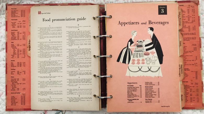 a vintage cookbook binder laying open on a floral-print cloth