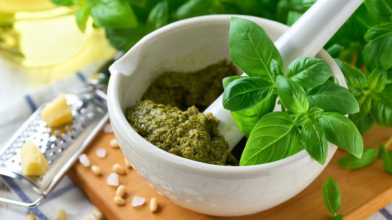 A small jar of basil pesto garnished with a fresh leaf