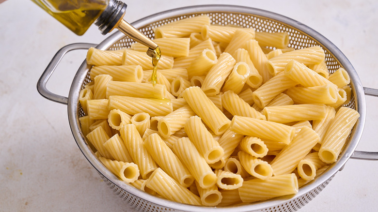 drizzling oil over drained pasta