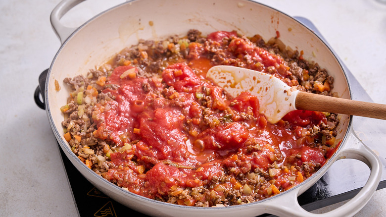 crushing tomatoes in skillet