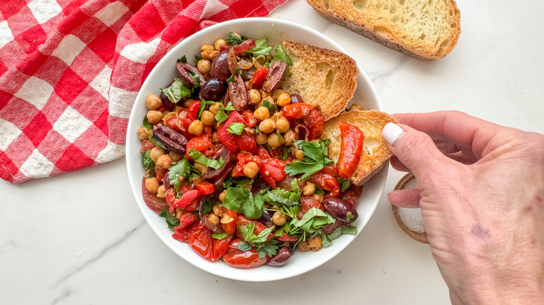 hand dipping bread into Mediterranean chickpea bowl