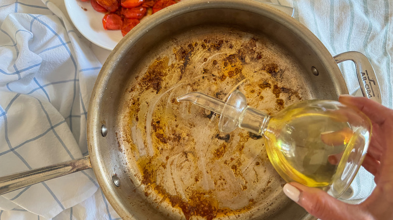 hand adding oil to pan