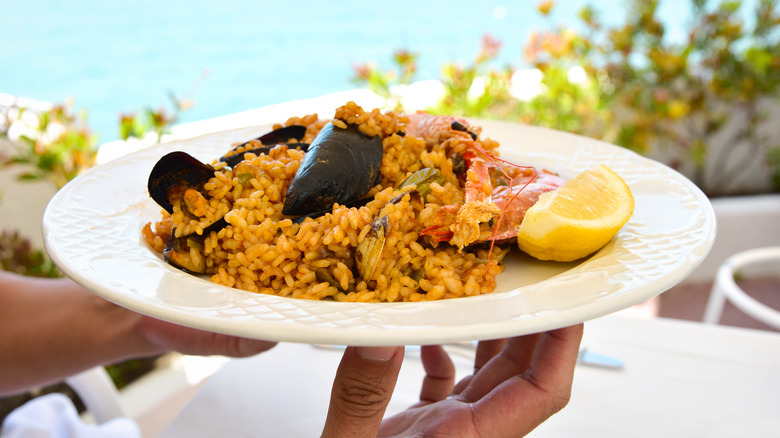 Hands holding plate of paella