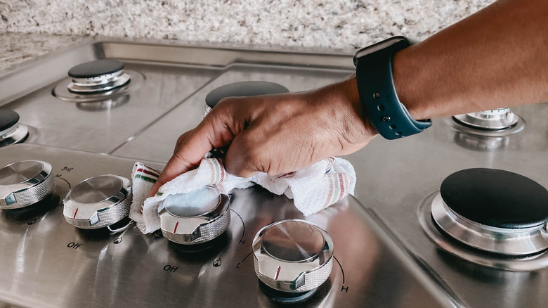 Male hand wiping out stove with a cloth