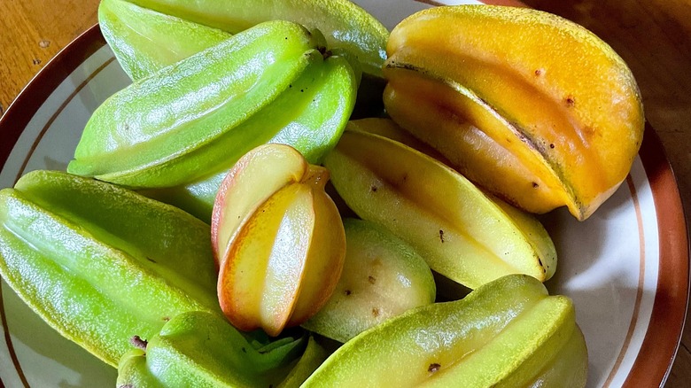 Several star fruit on a white and brown plate
