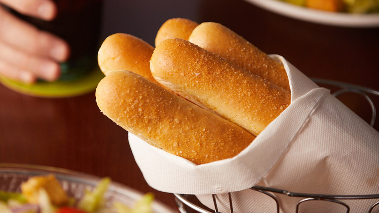 A basket of wrapped Olive Garden breadsticks on a table at the restaurant