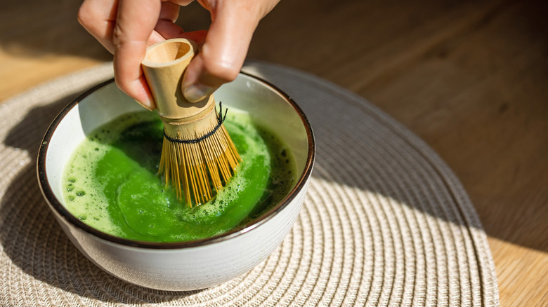 Person frothing matcha in a bowl