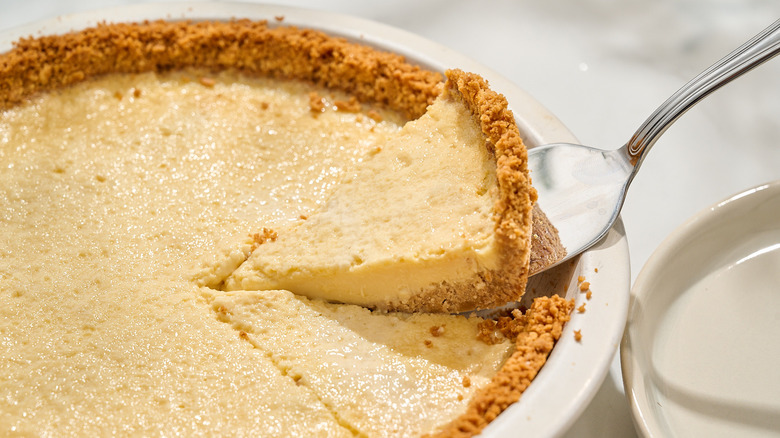 lifting slice of pay de queso out of pie pan