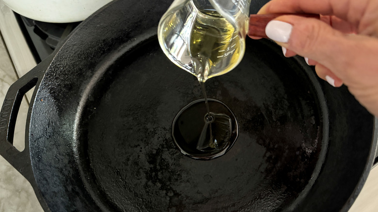 hand adding oil to pan