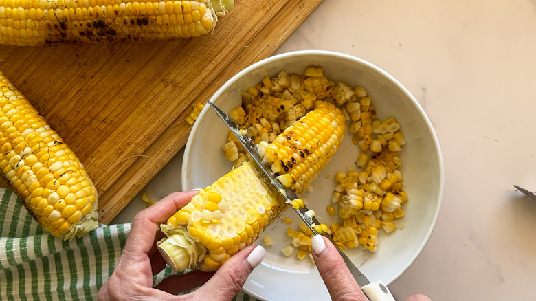 hand cutting off the kernels
